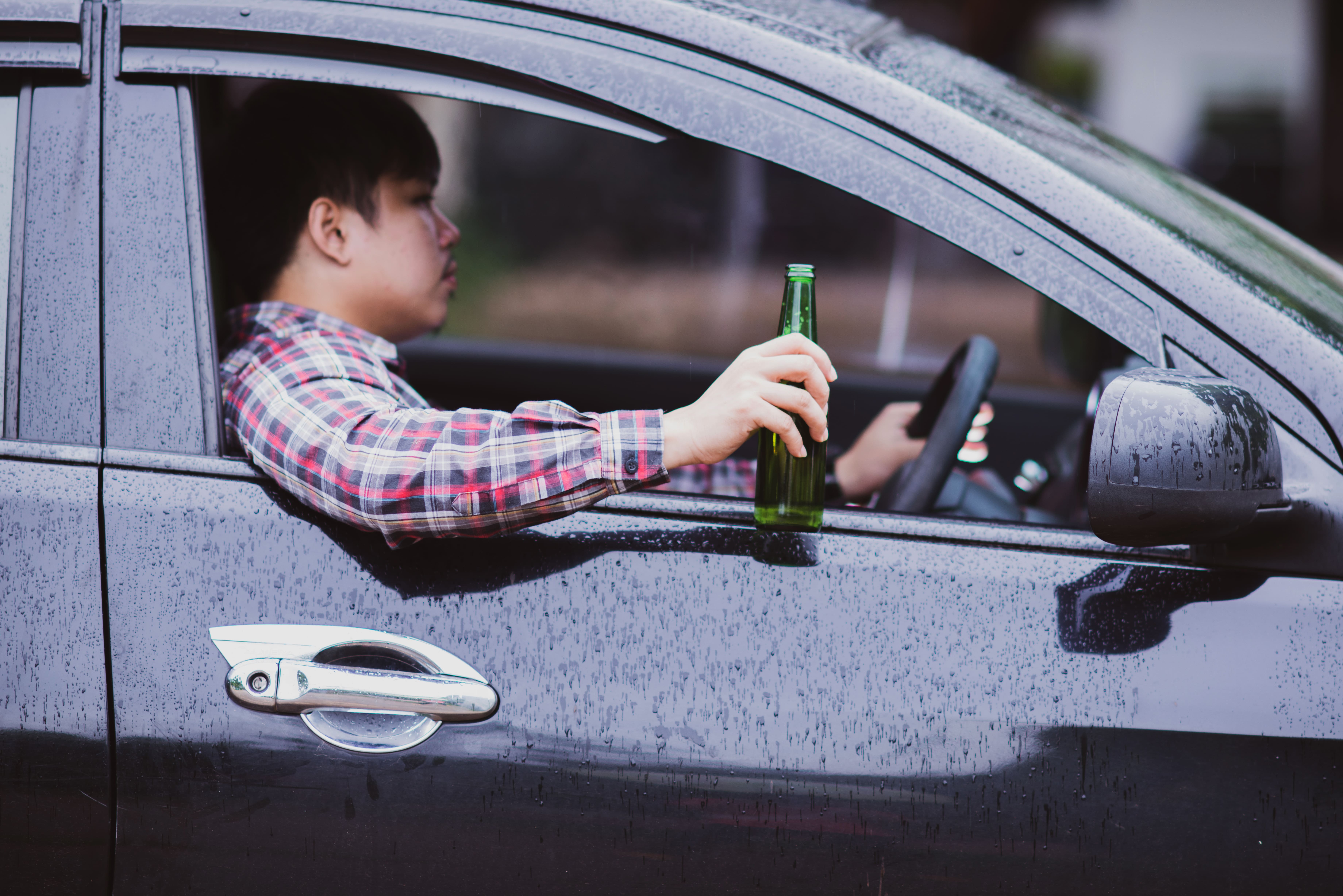 asian-man-holds-beer-bottle-while-is-driving-car (1).jpg